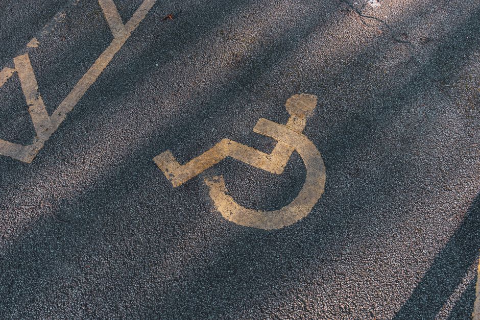 Close-up of an asphalt parking spot with a yellow wheelchair symbol for accessibility.