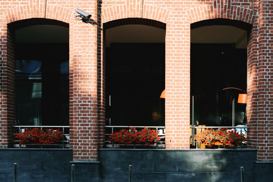 Red brick exterior with floral boxes and surveillance camera.