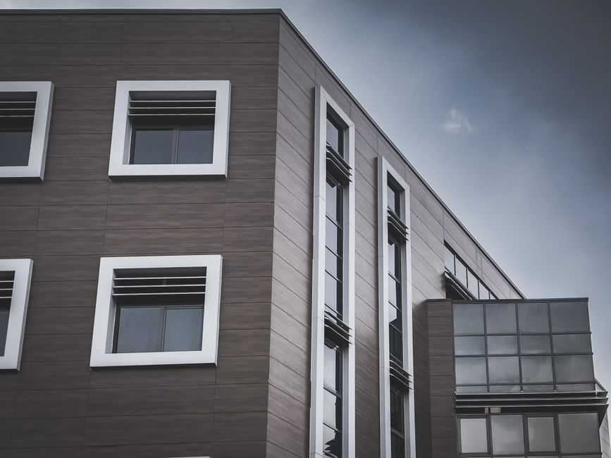 A modern apartment building with a geometric facade, featuring glass and clean lines under a clear sky.