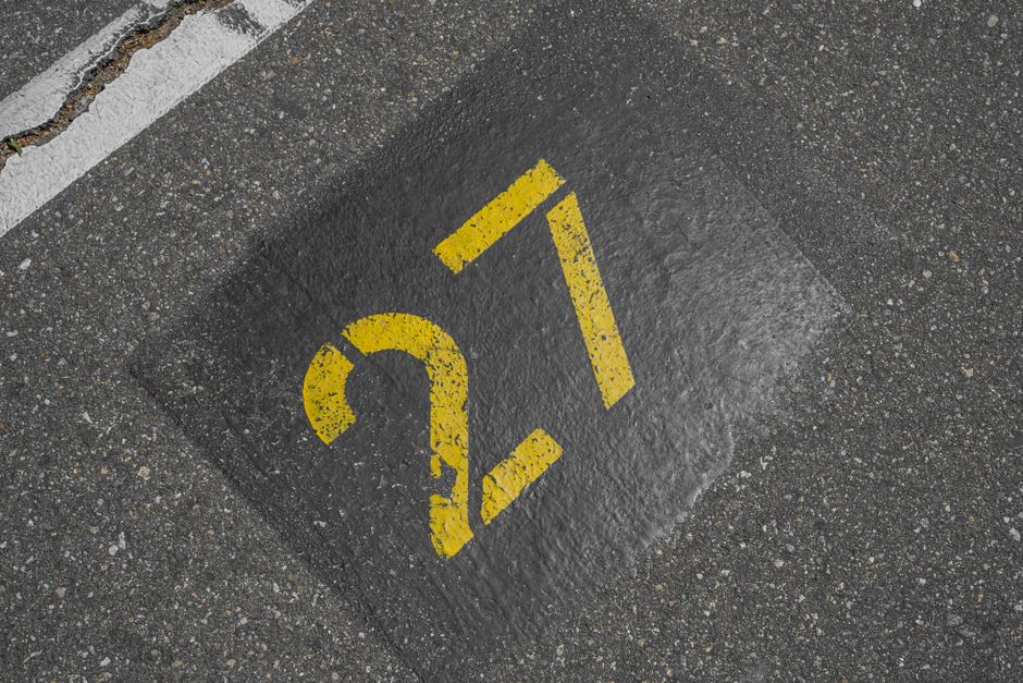 Close-up of the number 27 on asphalt in a parking lot, showing urban street details.