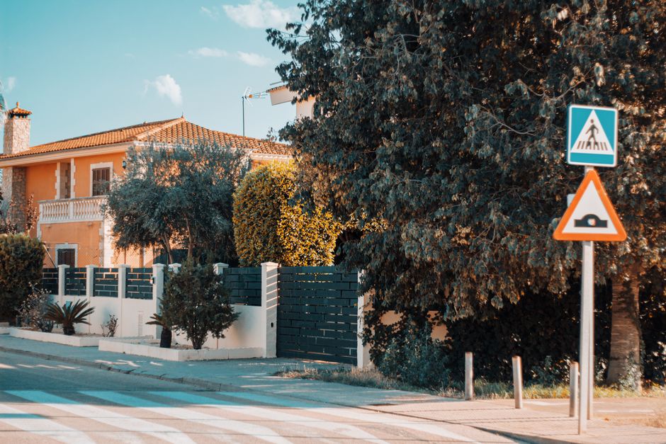 Beautiful Mediterranean style house in Mallorca with lush greenery and street signs under a bright sky.