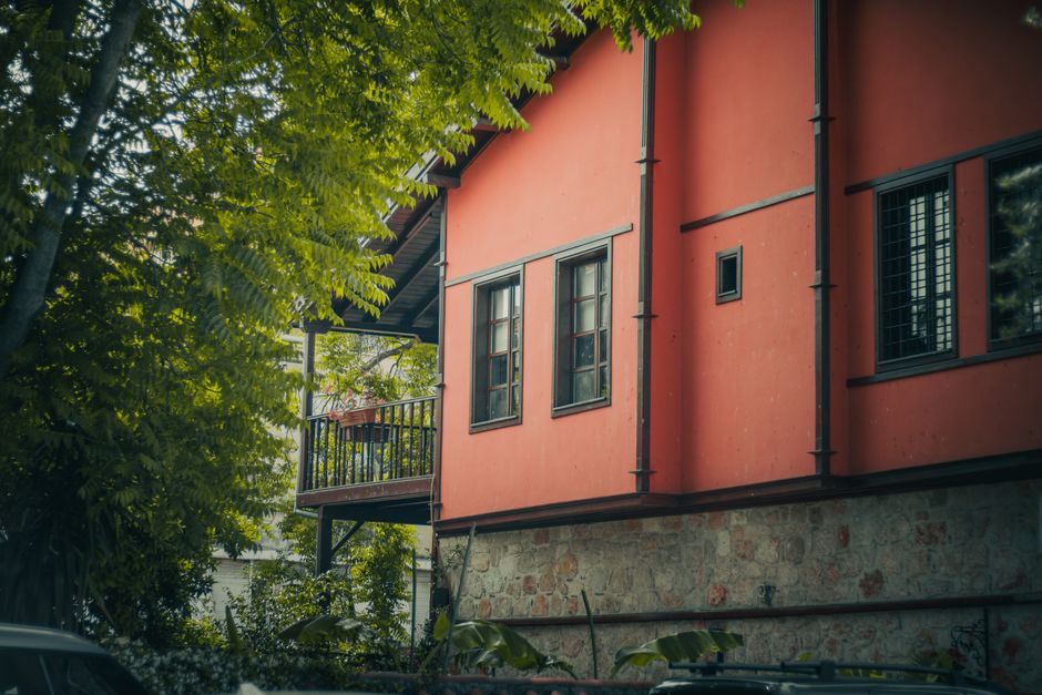 A traditional red house surrounded by lush foliage, evoking a feeling of tranquility and nature.