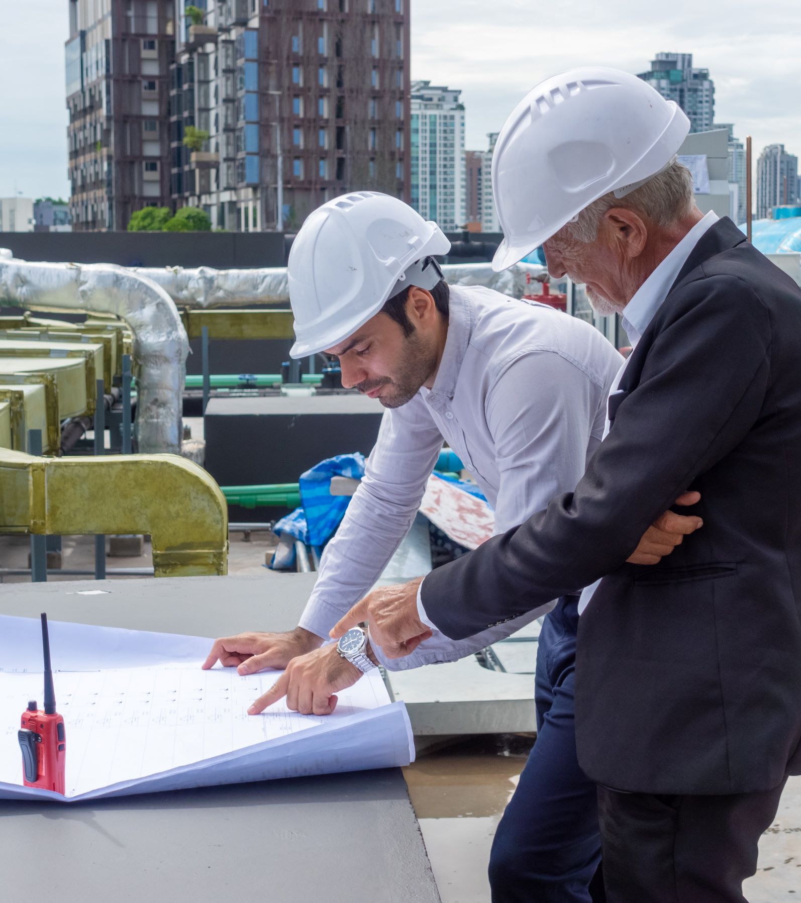 Project engineers in hardhats discussing project plan and blueprints