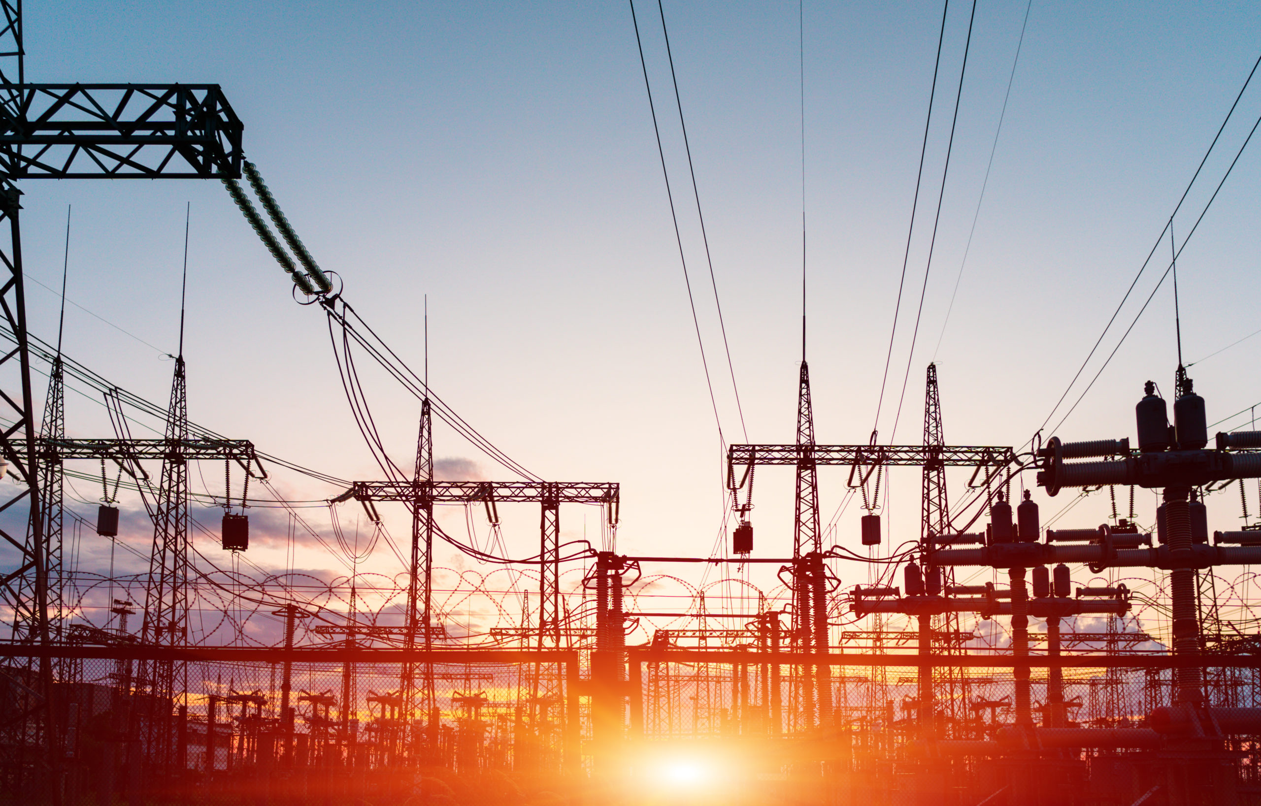 Silhouette of electricity lines with sunset in background.