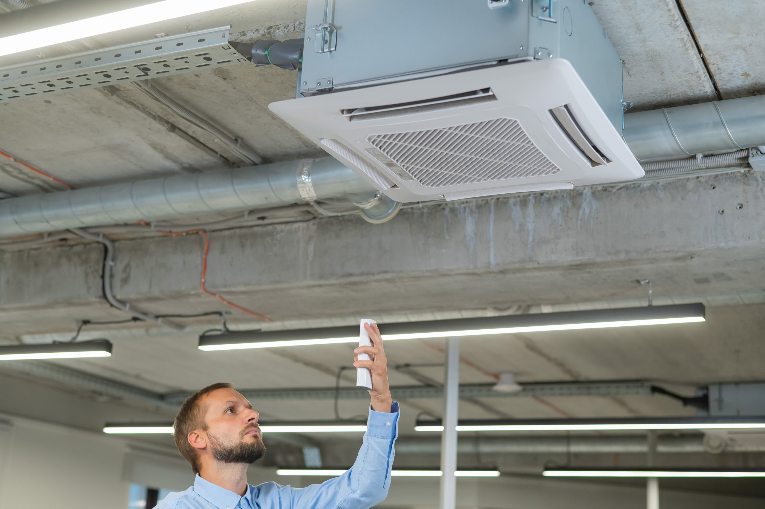 Man controlling the air conditioner in the office via a remote