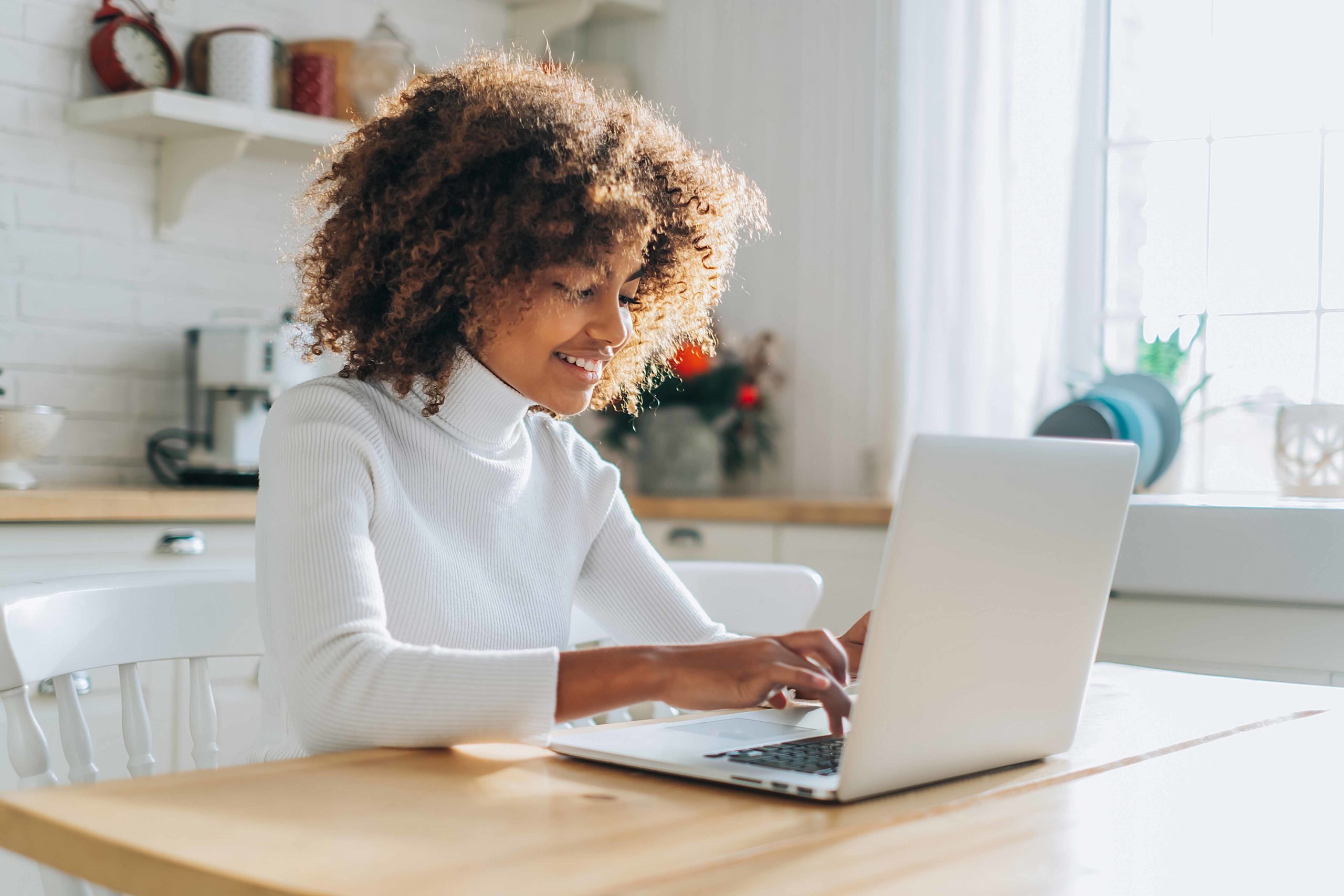 Concentrated and excited dark skinned young buyer with trendy hair looks in laptop smiles and enjoys online shopping closeup