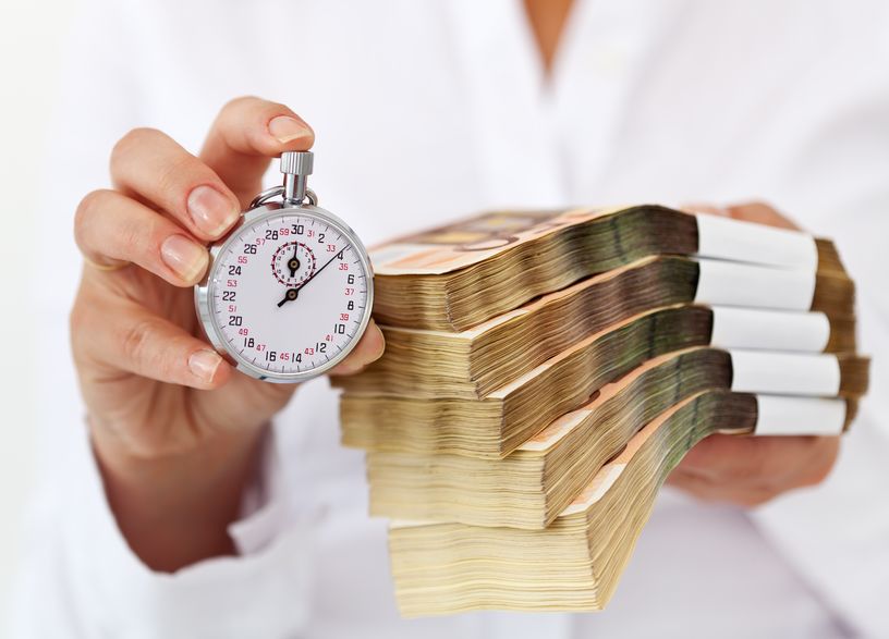22140112 - limited time offer concept with stack of money and stopwatch in woman hands - shallow depth