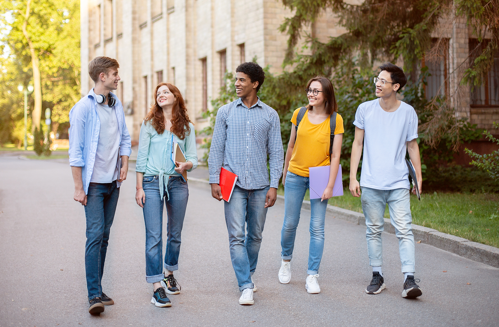 Five Multiracial High-School Students Walking And Talking In University Campus Outdoors. College Education Concept