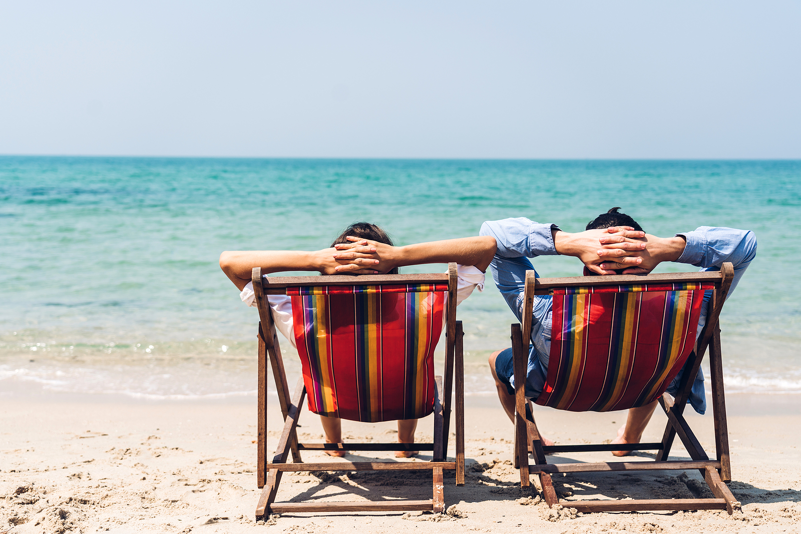 Romantic lovers young couple relaxing sitting together on the tropical beach and looking to the sea.Summer vacations