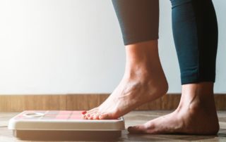 woman shown from her calves down, stepping barefoot onto a scale with her left foot.