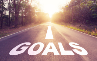 road leading to sunrise with the work GOALS written on the road