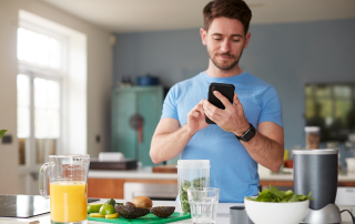 picture of man making a fiber rich smoothie and tracking this food on his cell phone