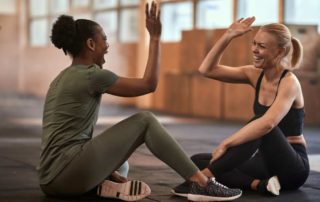 two women in a gym after a workout giving each other a high five