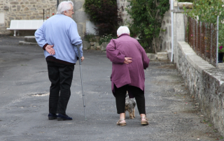 two seniors walking holding their backs in pain due to osteoporosis