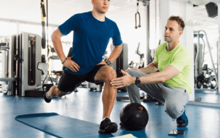photo of young man performing a suspension lunge with the guidance of a personal trainer