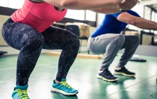 woman and male personal trainer performing body weight squats