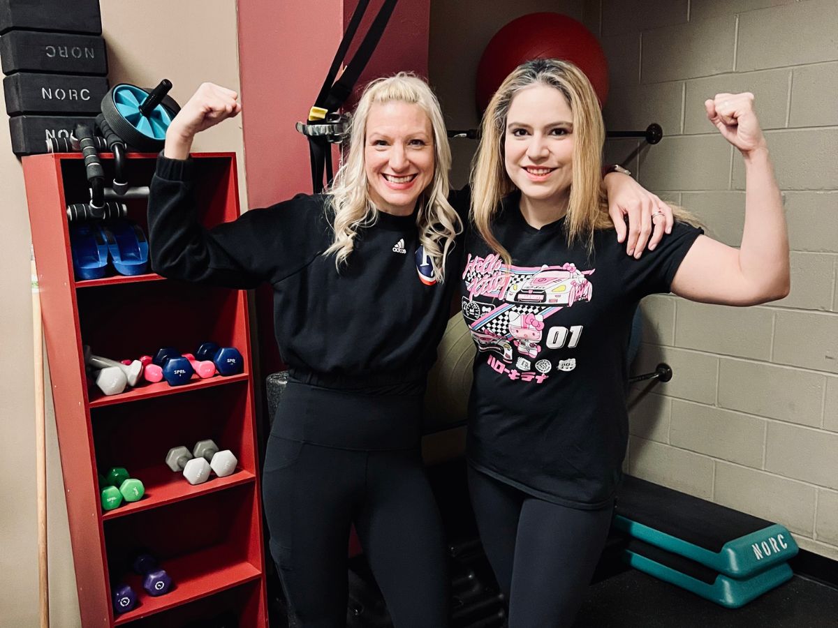 dr. meg kalsy and personal trainer lisa posing for a picture together flexing their arms