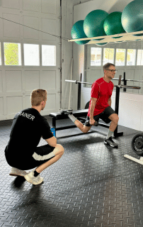 mike black doing a elevated split squat under the guidance of his personal trainer