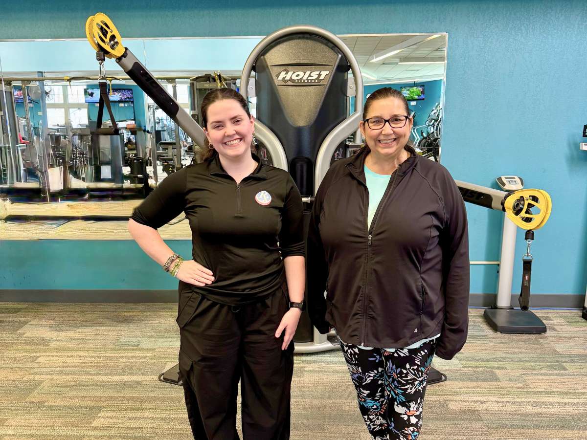 Personal trainer and client smiling together at Westlake Recreation Center in front of gym equipment.