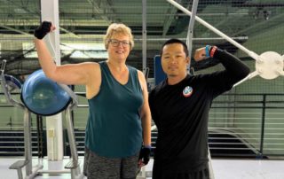 Rosanne and her personal trainer flexing their arms and smiling after a workout session at the Gemini Center gym.