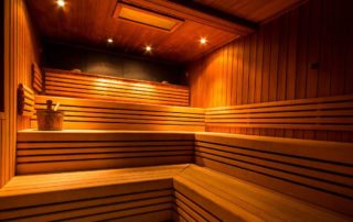 Modern wooden sauna with tiered seating and warm ambient lighting, ideal for relaxation and recovery.