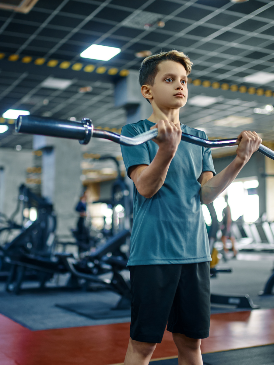 teen strength training classes Teen boy performing bicep curls in a gym during a Teen Strength Training class at Reminderville Athletic Club.